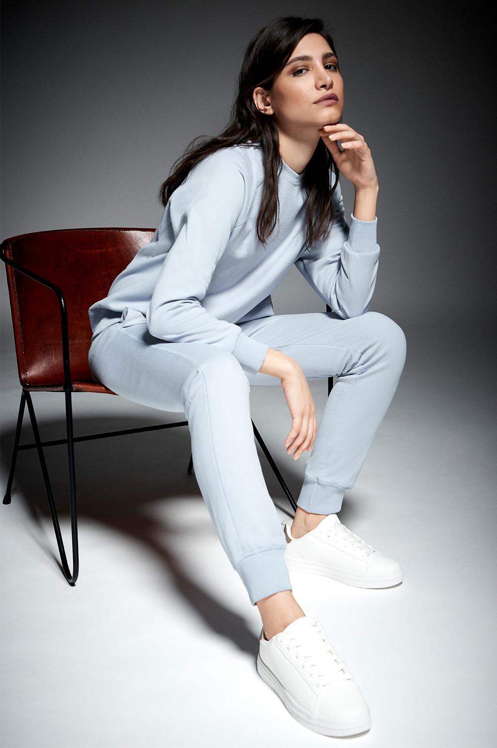 Model wears baby blue tailored joggers with matching sweatshirt and white trainers